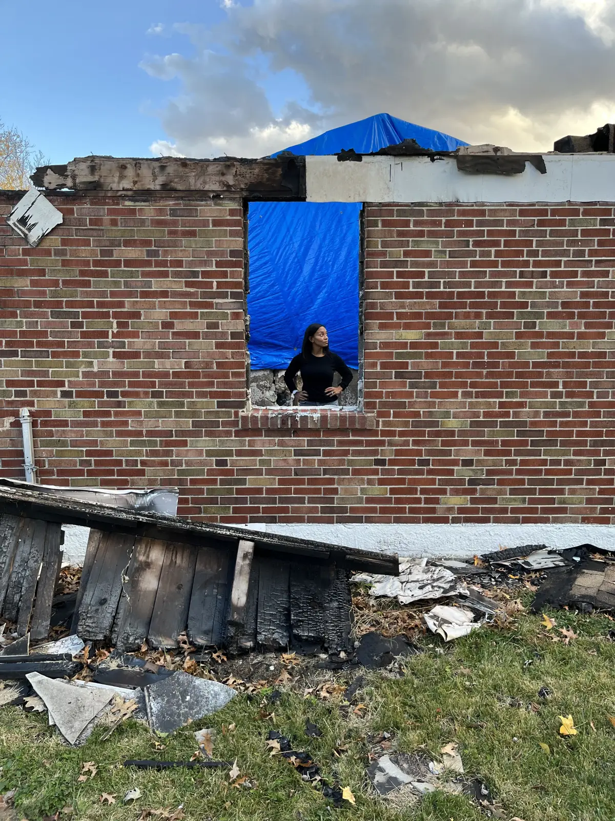 Burned-out walls under a tarp